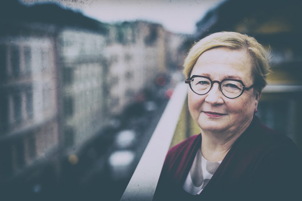 Riitta Leppiniemi seisoo parvekkeella ja katsoo kameraan