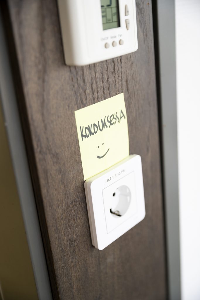 Hanne Aho on jättänyt toimistonsa ovenpieleen post it -lapun, jossa lukee "Kokouksessa :)".