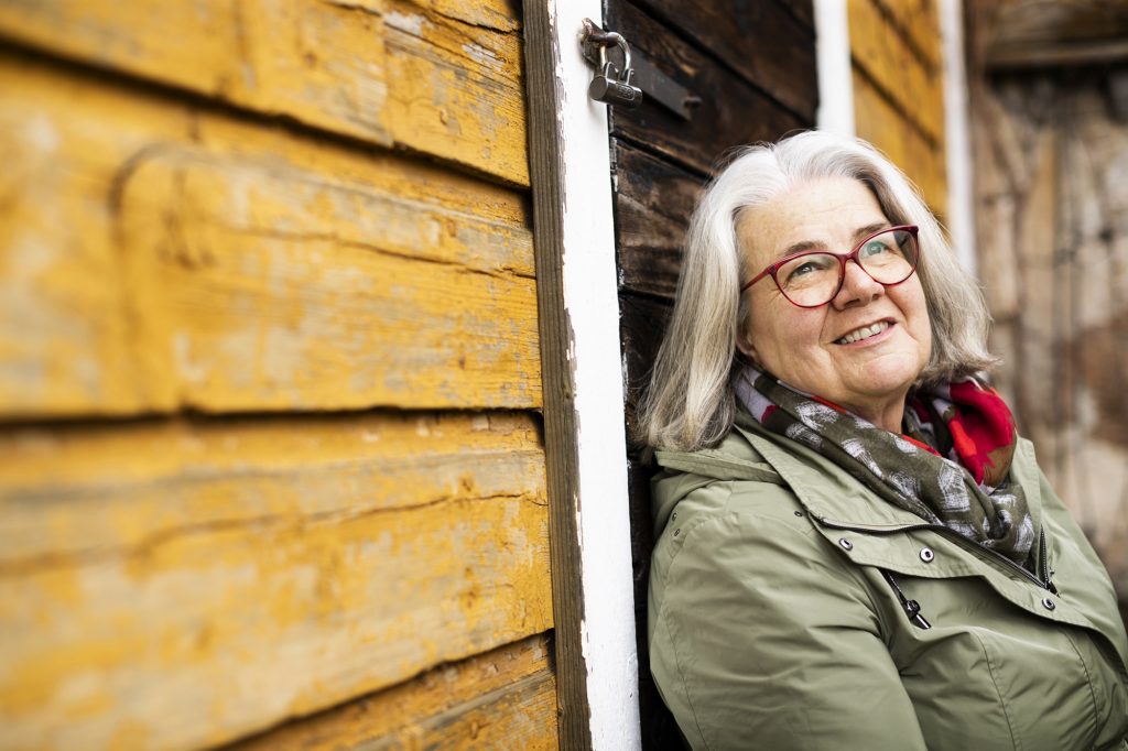 Kerstin Kronvall nojaa hirsisen talon seinään ja katsoo yläviistoon, kuin tulevaisuuteen.